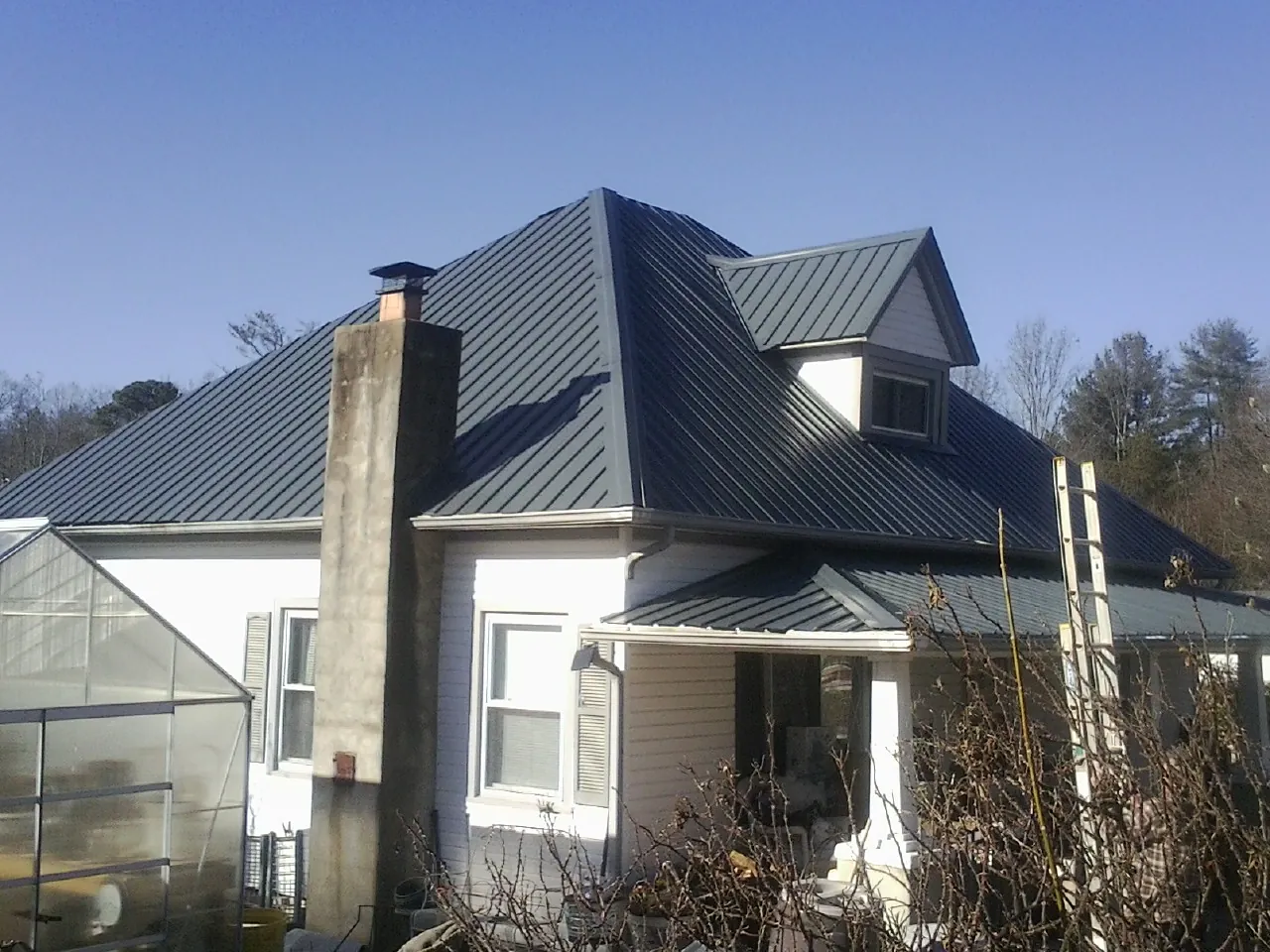 Dark blue standing seam metal roof on a white farmhouse with dormer — Slate & Tile Roof Repair by Roofing Brothers in Borrego Springs