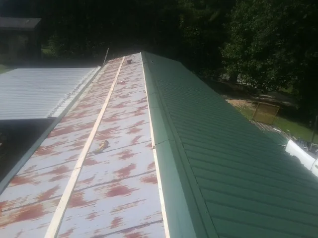 Old rusted panels beside newly installed green metal roofing — Wind Damage Roof Repair by Roofing Brothers in Borrego Springs