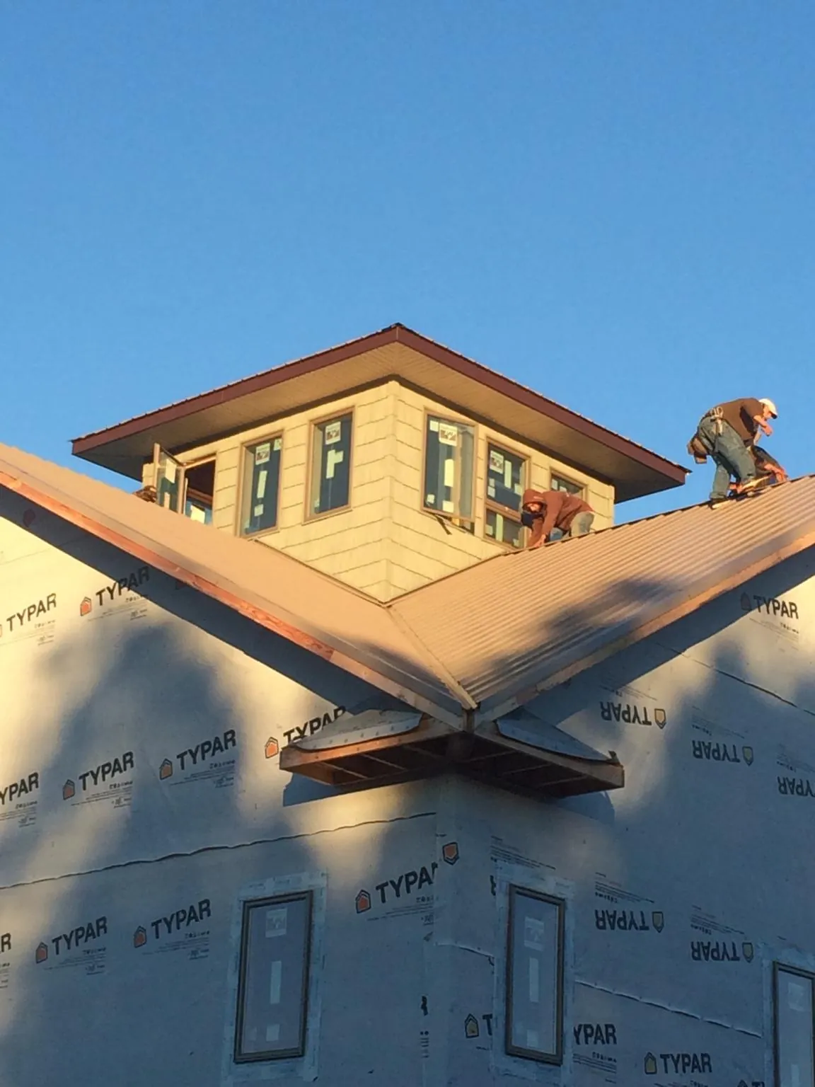 Roofers working around a rooftop cupola on a new metal roof at sunset — Roof Waterproofing in Borrego Springs by Roofing Brothers